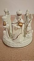 Front and angle view of the white ceramic nativity scene candle holder displaying the detailed figures and gold accents