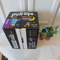 Photo of the full sealed box of Huggies Pull-Ups Night-Time extra absorbency training pants size 2T-3T with 68 count, alongside the two Disney The Good Dinosaur insulated sippy cups in packaging with green and blue lids.