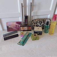 Full lot with all makeup items and cosmetic bag photographed on table against white cabinet doors.