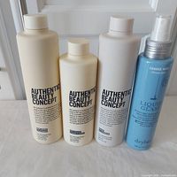 Four bottles of hair care products arranged in a row on white cloth with white door background