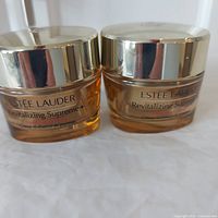 Two Estee Lauder Revitalizing Supreme+ jars side by side, front view showing product name.