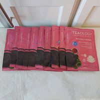 Ten pink sealed Teaology face and neck mask packets laid out side by side.
