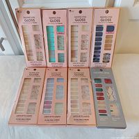 Display of eight Dashing Diva Gloss Ultra Shine Gel Palettes, showing nail strip colors and patterns in packaging