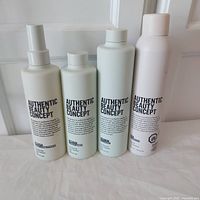 Four Authentic Beauty Concept haircare bottles photographed on a white surface with light background, showing front labels and bottle shapes.