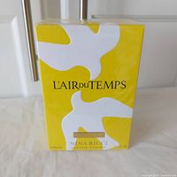 Front view of the yellow retail box featuring white dove and brand name L'Air du Temps by Nina Ricci, 50ml size