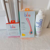 Billie Malibu starter kit box, additional razor refills, and shave gel bottle arranged on floor