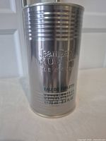 Front view of silver metal tin packaging embossed with brand and product name.