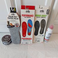 Full lot photo showing 2 tins of shoe polish, 3 different styles of mb insoles, and a can of footwear freshener, all new in packaging.