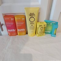 Lot contents showing all five sunscreen and lip balm products in their sealed packaging arranged in a row.
