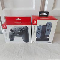 Front view of the boxed Nintendo Switch Pro Controller and Joy-Con Charging Dock, both new and sealed.