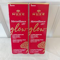 Photo of two sealed boxed tubes of Nuxe Merveillance Lift Glow Firming Radiance Cream 50ml each, front view of the product packaging.
