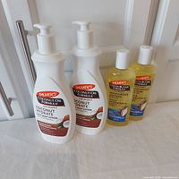 All four bottles arranged in a row, two larger white lotion bottles with pumps and two smaller clear bottles with yellow oil, showing brand and product type.