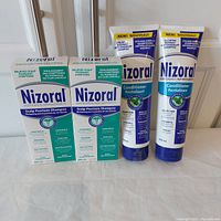 Full view of 2 boxed Nizoral Shampoo bottles with 2 tubes of conditioner in front.