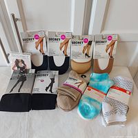 Full lot of Secret Collection hosiery and accessories on white surface showing all packaged items.