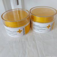 Two sealed containers of StriVectin TL Advanced Tightening Neck Cream with clear lids and yellow-white labels.