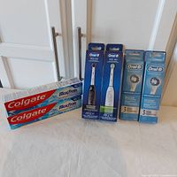 Lot arranged showing two Colgate Max Fresh toothpaste tubes, two Oral-B Pro 100 toothbrush boxes (charcoal and FlossAction), and two Oral-B Precision Clean replacement brush head packs, all boxed and sealed.