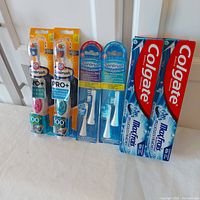 Photo showing full lot with two electric toothbrush packages (Extra White and Deep Clean), two replacement brush head packs (Clean and Whitening), and two Colgate Max Fresh toothpaste tubes.