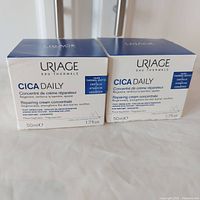 Two boxes of Uriage Cica Daily Repairing Cream Concentrate side by side, showing front packaging details such as product name, quantity, and key ingredients.