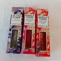 Three boxed Winky Lux lip oils shown together on a white background.