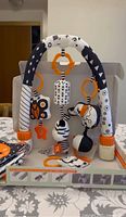 Photo of the baby gym fully assembled showing black and white arches with hanging toys including a butterfly, zebra, ball, etc.