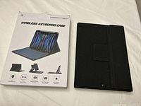 Photo showing black wireless keyboard case alongside original product packaging explaining features like magnetic attachment, adjustable stand, and compatibility with iPad.