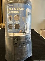 Front of packaging showing seat and back cushion with icon-based descriptions of premium memory foam, washable cover, adjustable straps, and non-slip bottom.