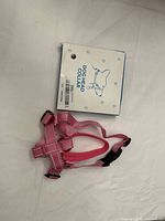 Pink adjustable dog head collar displayed with its product packaging showing the label and design.