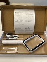 Magnifying glass in open box with USB cable and instruction sheet visible, showing design and included accessories.