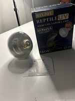 Photo of MIXJOY branded Reptile UV Mercury Vapor Lamp bulb standing upright near box and instruction sheet, showing front of box and bulb details.