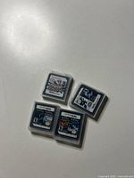 Four Nintendo DS game cartridges in original clear plastic cases displayed on a white surface. Game labels visible indicating titles including Pokémon games.