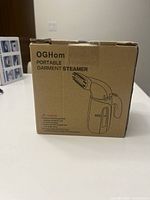 Box front showing product image, OGHom Portable Garment Steamer branding, and caution info.