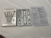 Photo of the grooming kit with all attachments and USB charging cable in original box alongside the instruction sheet, showing the complete contents of the kit.