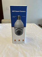 Front view of the WiFi Smart Camera box showing camera image and main features listed: intelligent dual light dot, 2-way audio, motion detection, app control, and human shape detection.