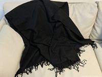 Black cashmere throw draped over light-colored couch.