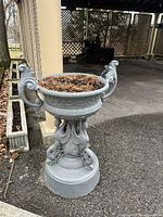 Full view of the gray painted cast iron urn on its pedestal, showing swan-shaped handles and ornate relief details.