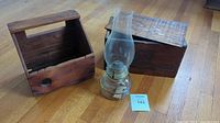 Photo of all three items on wooden floor: wooden crate, glass oil lamp, and shoe shine box