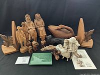 Photo of all items in the collection including linen figurines on driftwood, wooden carved older couple on rocking chairs, Quebec folk art wooden figures, maple leaf bookends, carved duck figure, driftwood and carved hound dogs and foal