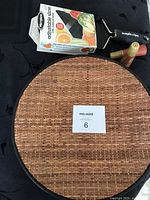 Photo showing four items: one round woven bamboo/plastic plate charger, boxed Microplane adjustable slicer, and two vintage teak salt and pepper shakers.