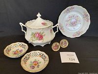 Photo showing Gloria fine porcelain floral plate, floral decorated tureen with lid, two Dresden line Schumann Bavaria pierced dishes, and two oval mini plates with Victorian scenes and holders.