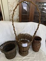 Photo showing all three baskets together - tall basket with arched handle in center, medium wider basket left, small narrow basket right