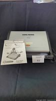 Top view of George Foreman Healthy Cooking Grill with instruction manual placed on it
