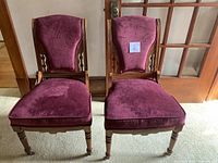 Pair of dark wood framed chairs with burgundy velvet cushion and backrest upholstery shown from front