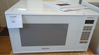 Front view of white Panasonic microwave oven showing large viewing window and control panel on the right.