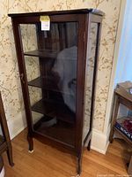 Front view of dark wood curio cabinet with glass door and interior shelves