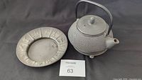 Cast iron black kettle with lid, handle, spout and zodiac tray beside it