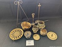 Full lot of vintage Italian brass and metal items arranged on black background including hat pin holder, ladle, candle holder, bowls, trays, and small holders.
