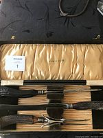 Full set of three carving utensils inside original presentation box with satin-lined interior and velvet holders. Exterior of box made of black material with gold accents.