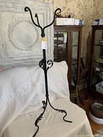 Full front view of the tall black ornate cast iron plant stand with curved legs and three hook arms.