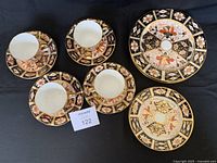 Four teacups with saucers and two plates on black background