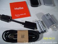 Amazon Fire Stick 4K with remote, power adapter, HDMI extender, two Amazon Basics AAA batteries, and user manual.